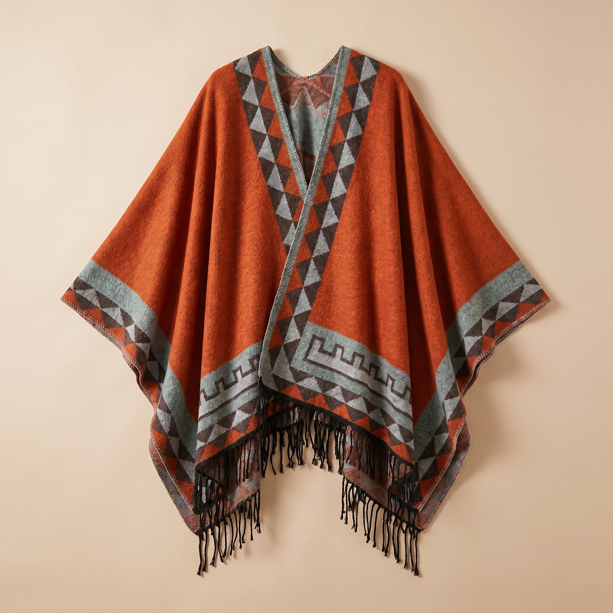 Poncho femme chaud à motif aztèque et franges orange vif, avec motifs géométriques gris et noirs, posé à plat