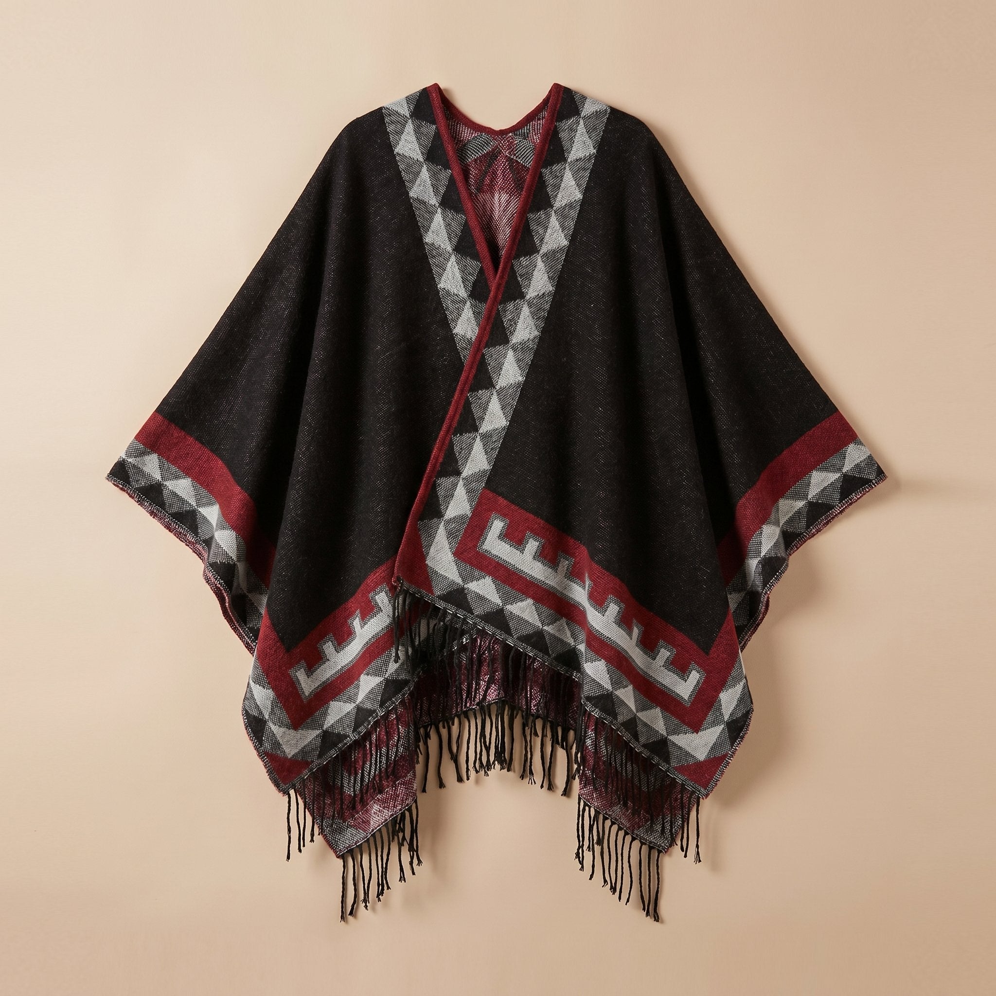 Poncho femme chaud à motif aztèque et franges noir, avec motifs géométriques gris et rouges, posé à plat