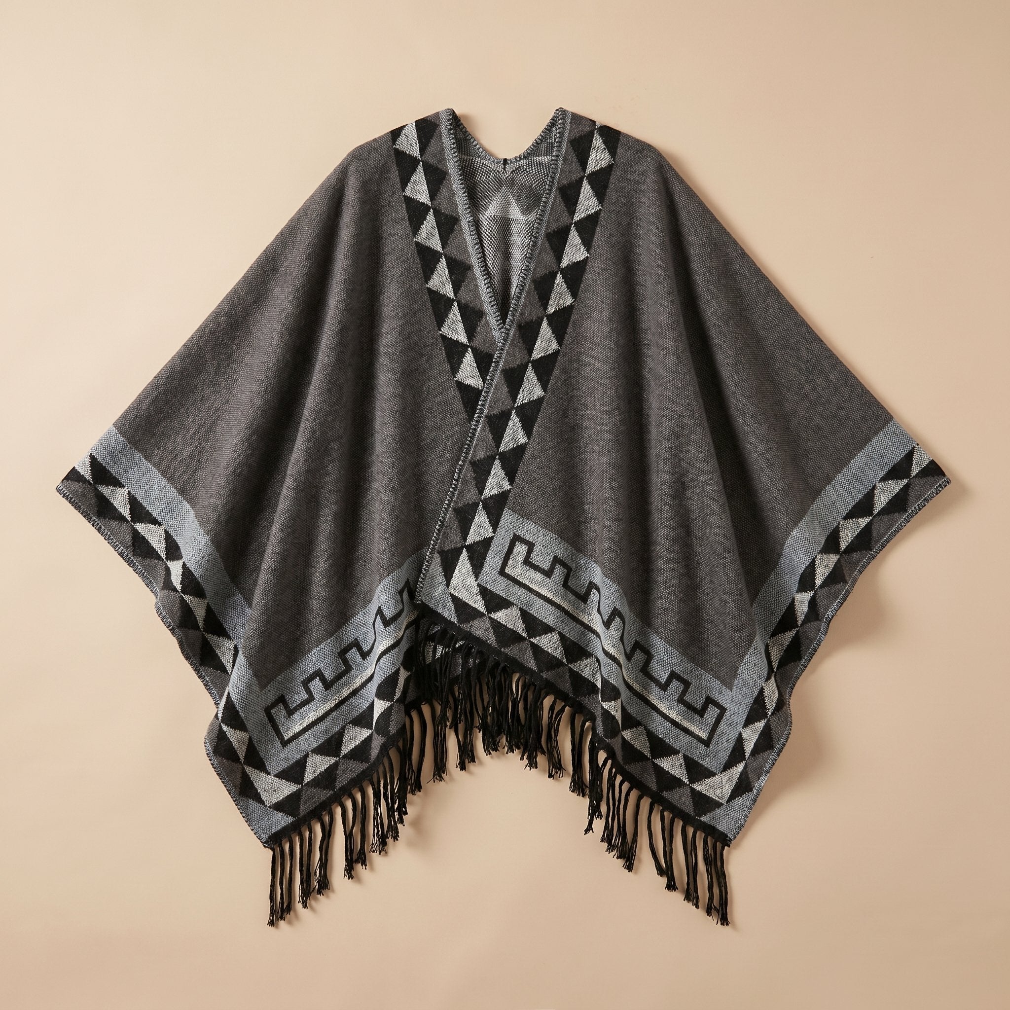 Poncho femme chaud à motif aztèque et franges gris foncé, avec motifs géométriques noirs et gris clair, posé à plat
