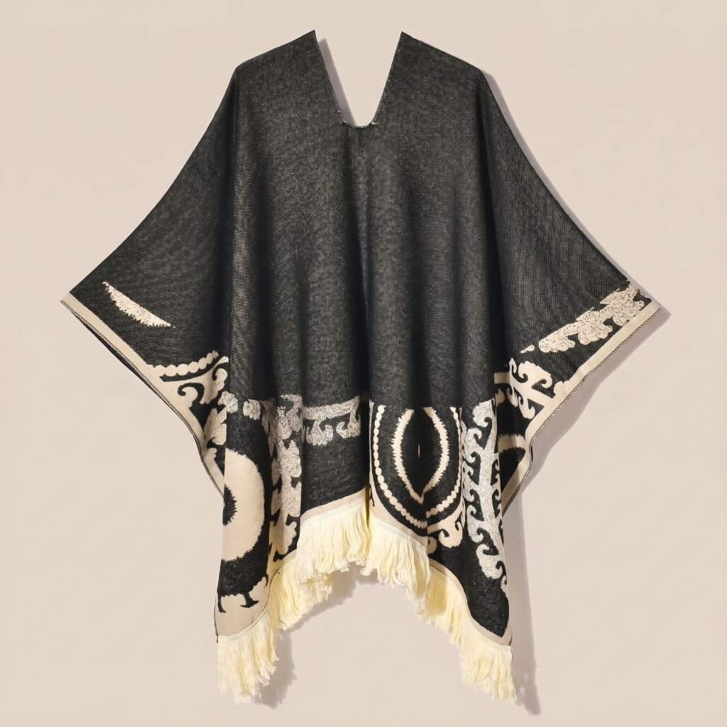 Poncho femme ethnique noir et crème à franges présenté à plat, vue de face, détaillant le col en V, les motifs et les franges