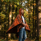 Poncho péruvien homme à capuche orange et noir, porté de profil par un homme en extérieur boisé