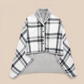 Poncho plaid à carreaux blancs présenté à plat sur un fond uni clair, montrant son motif et sa doublure.