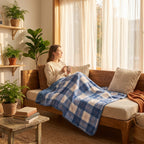 Poncho plaid à carreaux bleus drapé sur les jambes d'une femme regardant par la fenêtre depuis un banc.