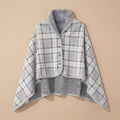 Poncho plaid à carreaux gris, présenté à plat pour montrer son motif et son côté réversible.