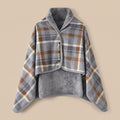 Poncho plaid à carreaux gris et brun présenté à plat, montrant le motif et la doublure douce.