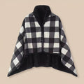 Poncho plaid à carreaux noir et blanc, présenté à plat sur un fond uni clair, vue de face.