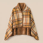 Poncho plaid à carreaux ocre posé à plat, montrant l'intérieur en fausse fourrure marron.