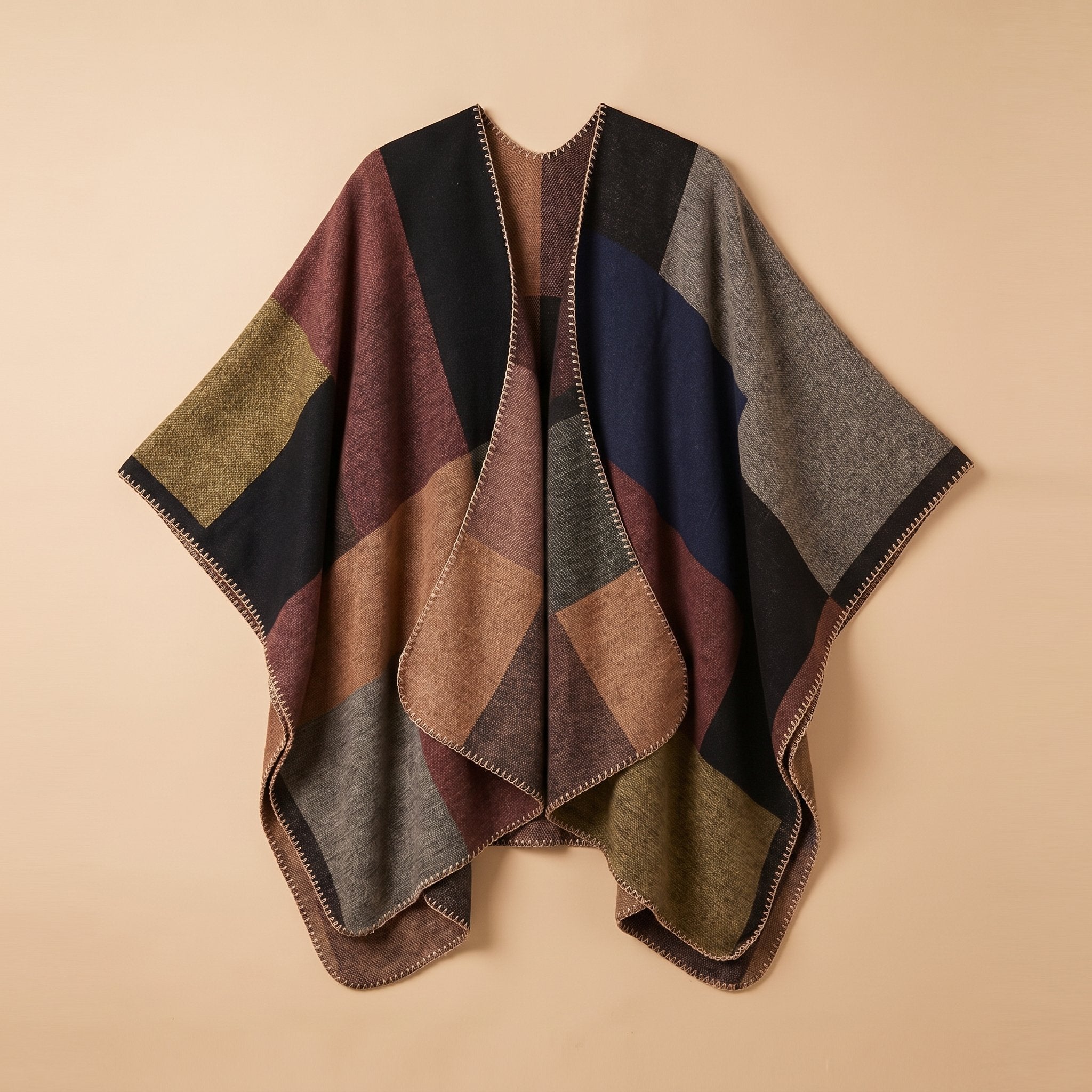 Poncho plaid colorblock camel posé à plat sur un fond uni beige clair.