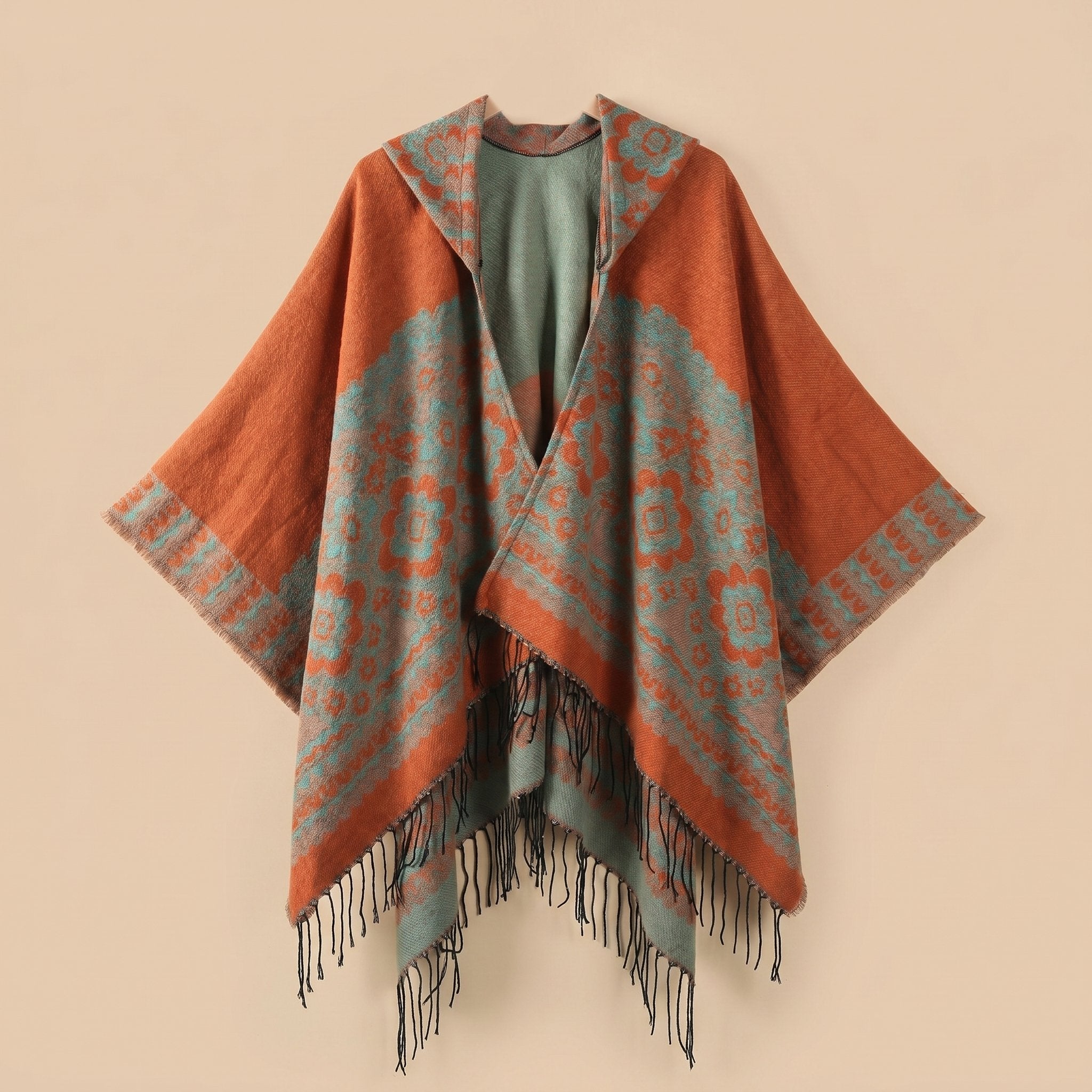 Poncho plaid à capuche motif bicolore, présenté de face avec des motifs floraux et des franges.