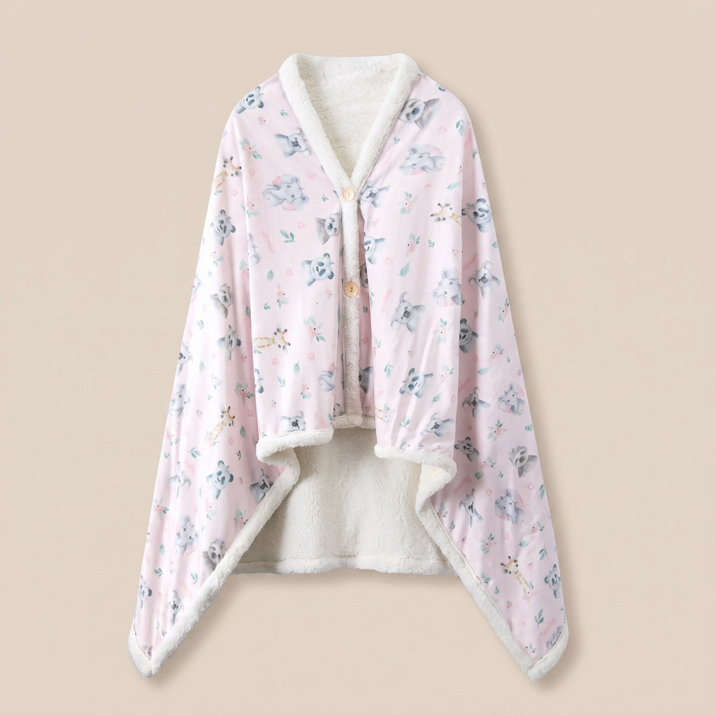 Poncho plaid Koalas et fleurs, vue a plat sur fond creme, imprime koalas gris sur rose pale et doublure sherpa ecrue.