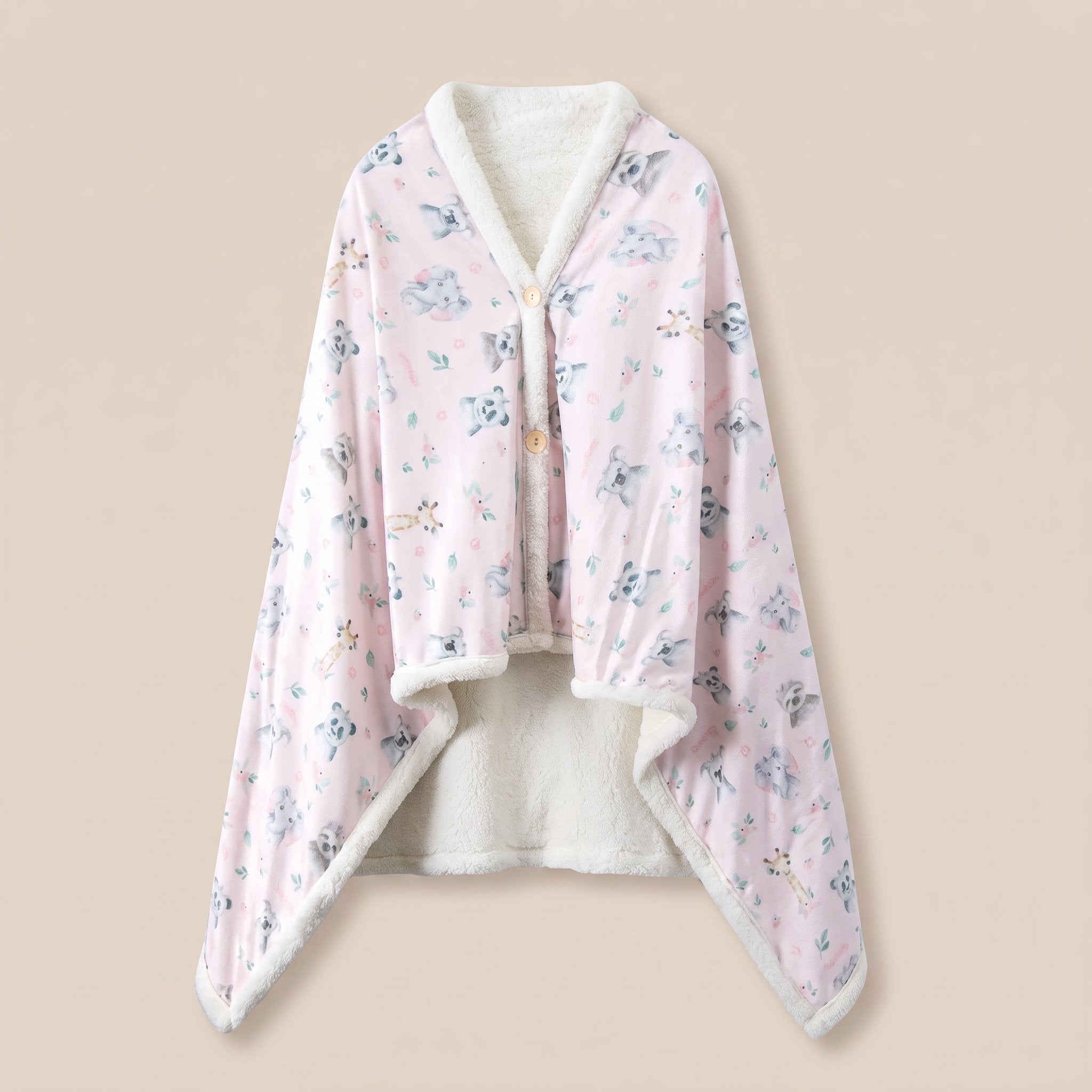 Poncho plaid Koalas et fleurs, vue a plat sur fond creme, imprime koalas gris sur rose pale et doublure sherpa ecrue.