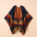 Poncho plaid à rayures bleues, oranges et rouges, étalé sur un fond beige clair et discret.