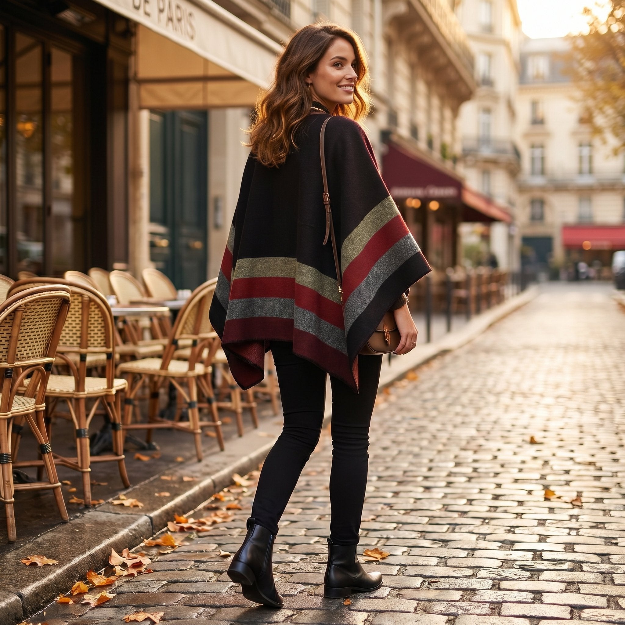 Poncho plaid à rayures rouges, noires et grises, porté par une femme marchant de dos en ville.