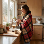 Poncho plaid tartan rouge porté par une femme préparant du café dans une cuisine moderne.