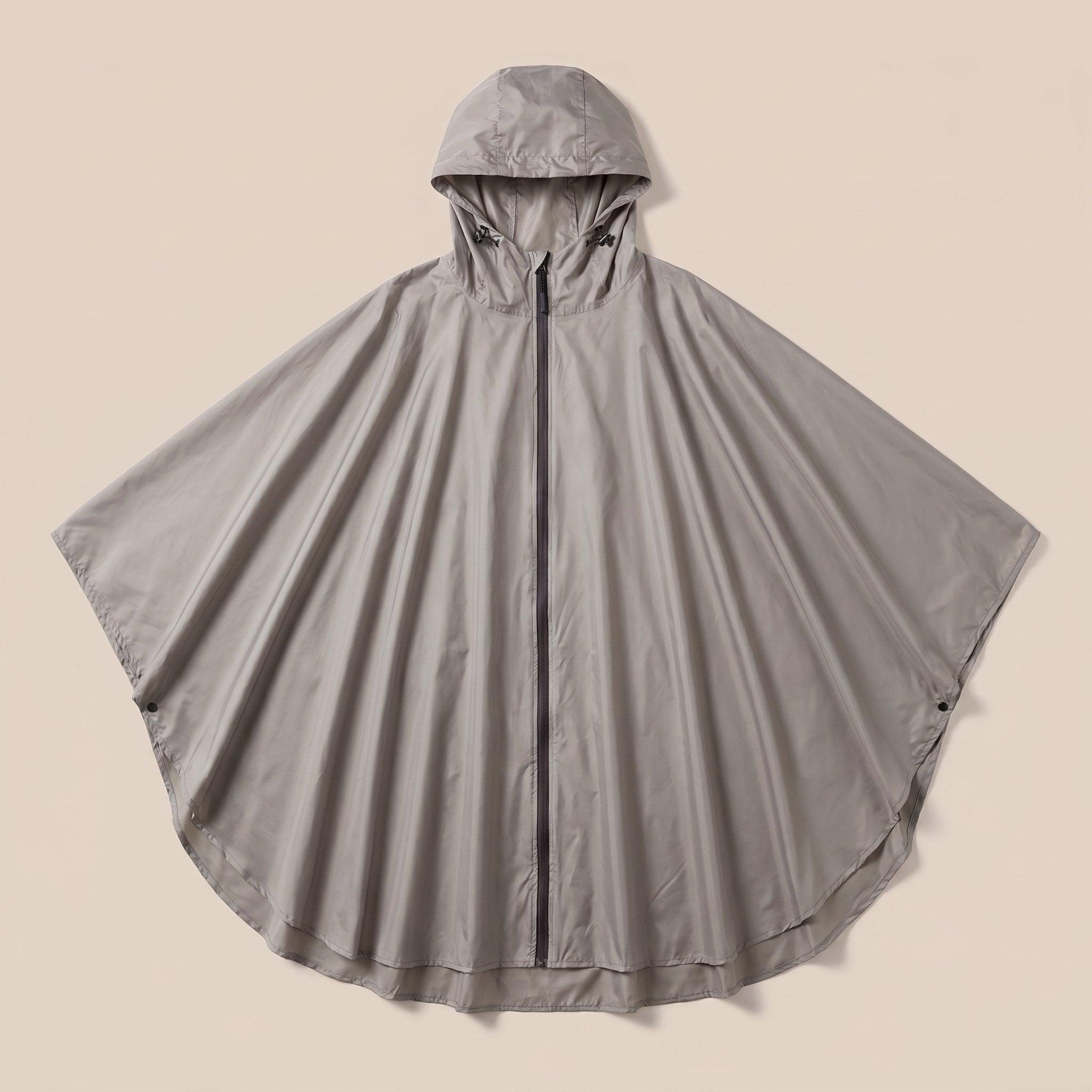 Poncho de pluie à capuche femme gris présenté à plat sur un fond uni