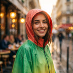 Poncho de pluie à capuche femme vert et orange, gros plan sur le visage souriant d'une femme portant la capuche relevée