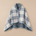 Poncho polaire à carreaux gris et blanc présenté à plat, révélant son intérieur doux et réversible.