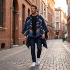 Poncho polaire à capuche motif ethnique marine, porté par un homme marchant dans une rue pavée.