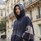 Poncho pull femme à capuche marine, porté par une femme en gros plan, la capuche relevée.