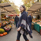 Poncho pull femme à capuche marine, porté par une femme marchant de profil dans un marché.