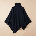 Poncho pull femme bleu marine, col roulé, étendu sur un fond clair.