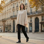Poncho pull femme beige, porté par une femme marchant sur un trottoir en ville.