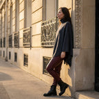 Poncho pull femme anthracite, porté par une femme de profil appuyée contre un mur.