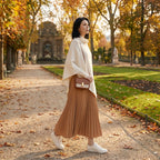 Poncho pull femme blanc cassé porté par une femme marchant dans un parc en automne.