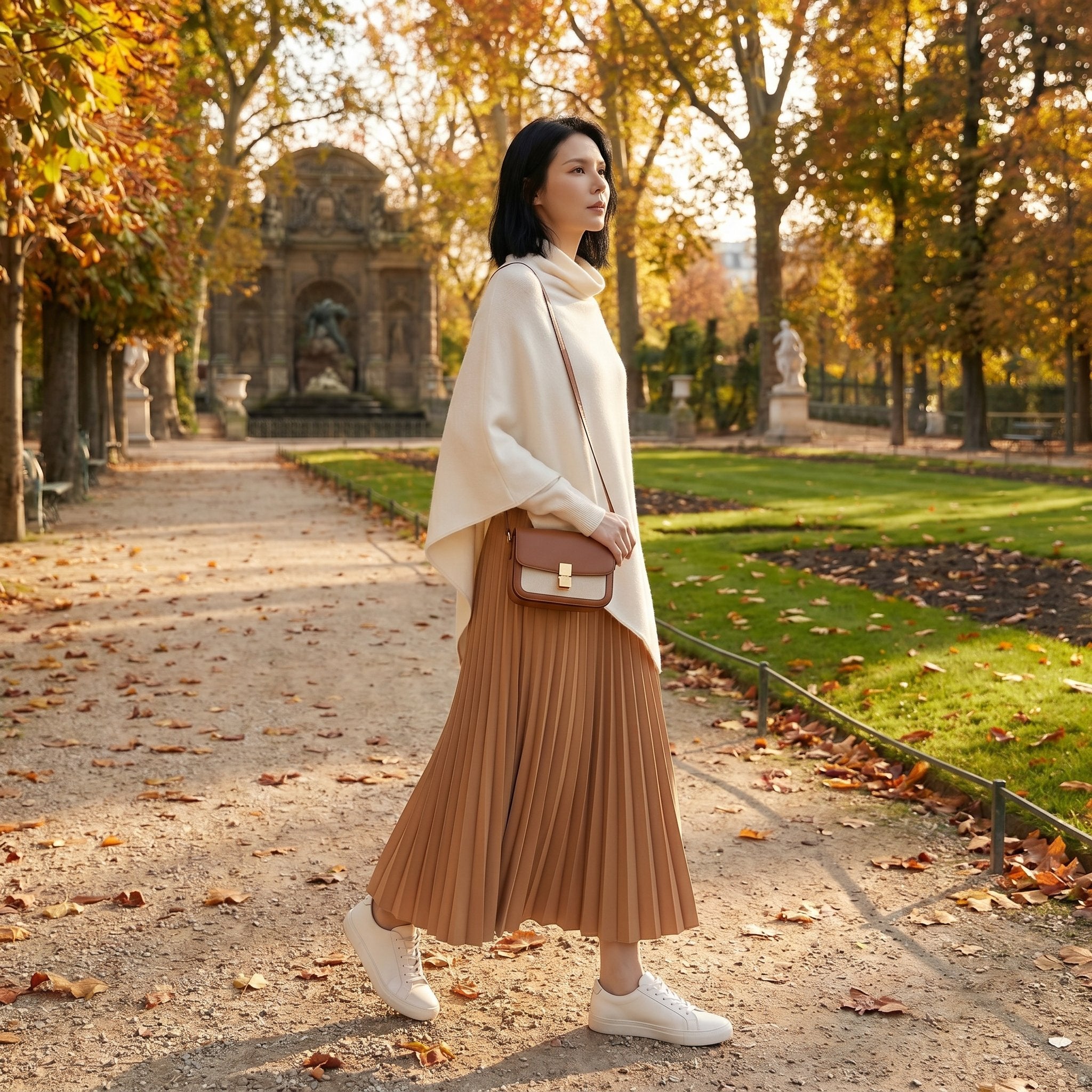 Poncho pull femme blanc cassé porté par une femme marchant dans un parc en automne.