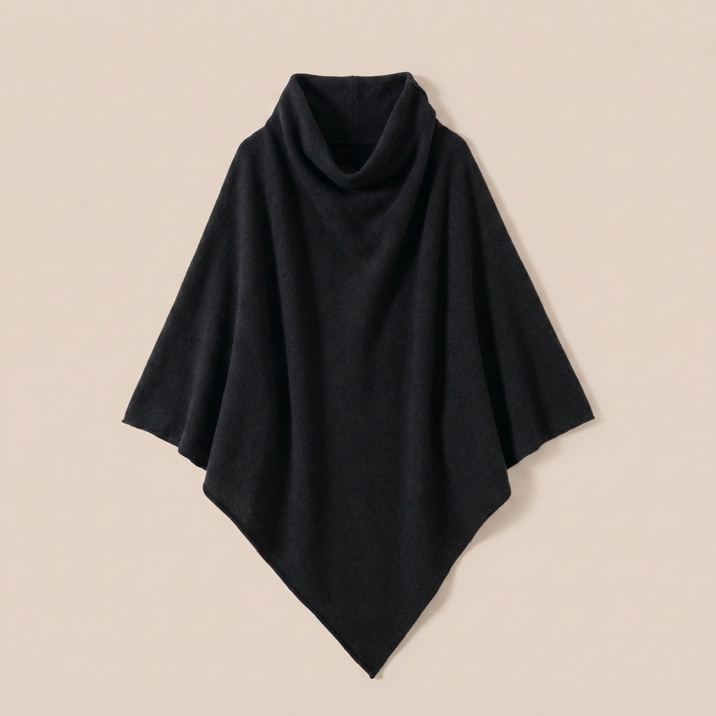 Poncho pull femme col roulé noir, posé à plat sur un fond clair et neutre.