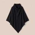 Poncho pull femme col roulé noir, posé à plat sur un fond clair et neutre.