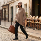Poncho pull femme beige porté par une femme marchant sur une rue pavée.