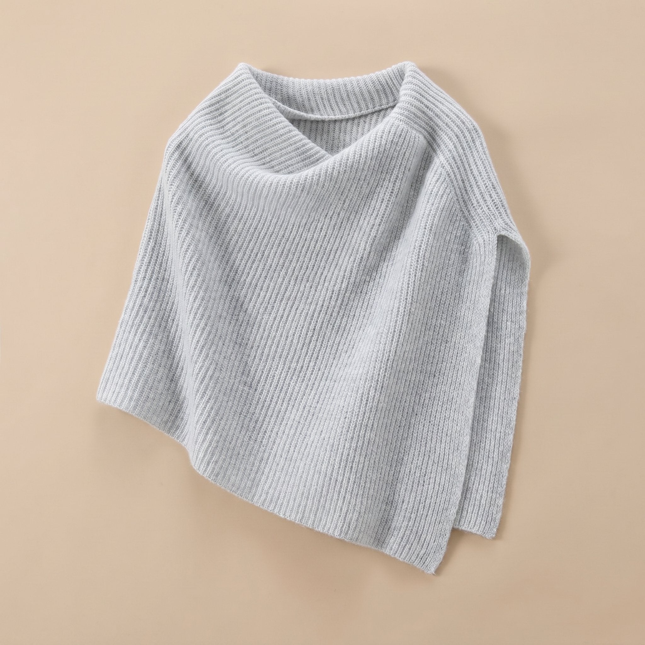 Poncho pull femme couleur gris clair, présenté à plat, avec un pli élégant du col.
