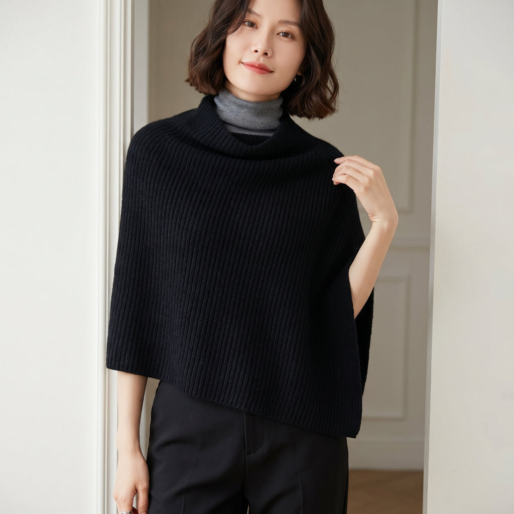 Poncho pull femme couleur noire, porté par une femme en intérieur, vue de face, cadrage serré sur le buste.