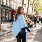 Poncho pull femme col roulé bleu clair, porté par une femme souriante se retournant dans la rue.