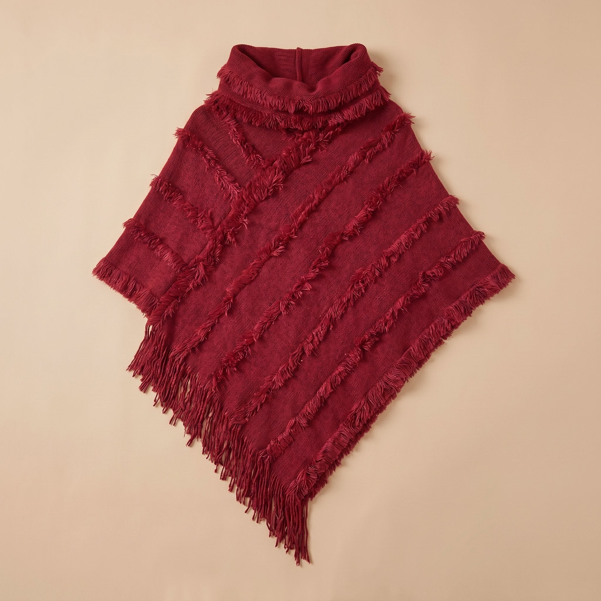 Poncho pull femme col roulé rouge bordeaux, mis en valeur par un éclairage doux.