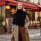 Poncho pull femme noir, porté par une femme debout en extérieur devant un café.