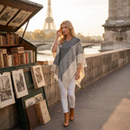 Poncho pull femme colorblock gris et blanc, porté par une femme marchant le long d'un quai.