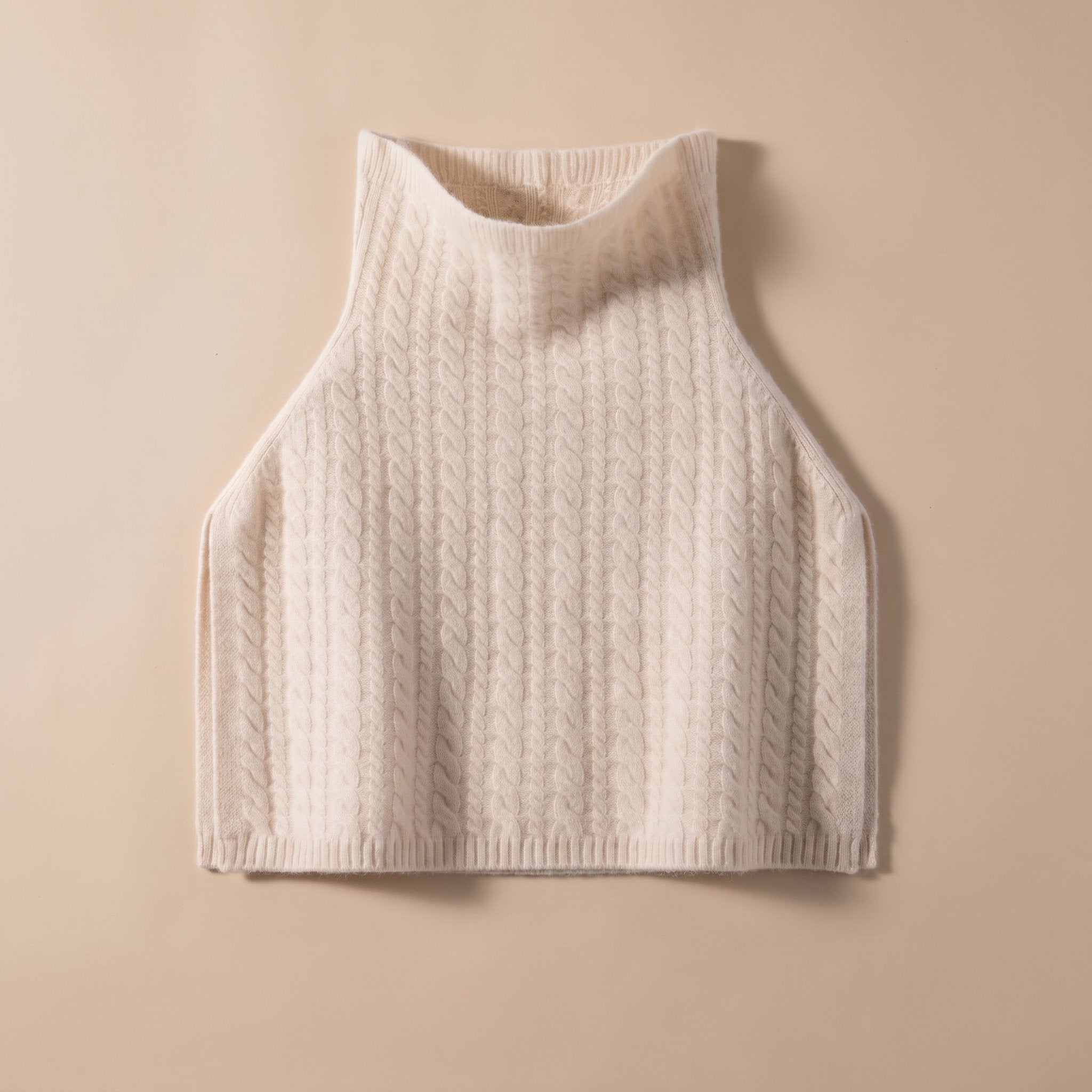 Poncho pull femme maille torsadée crème, présenté à plat sur un fond uni clair.