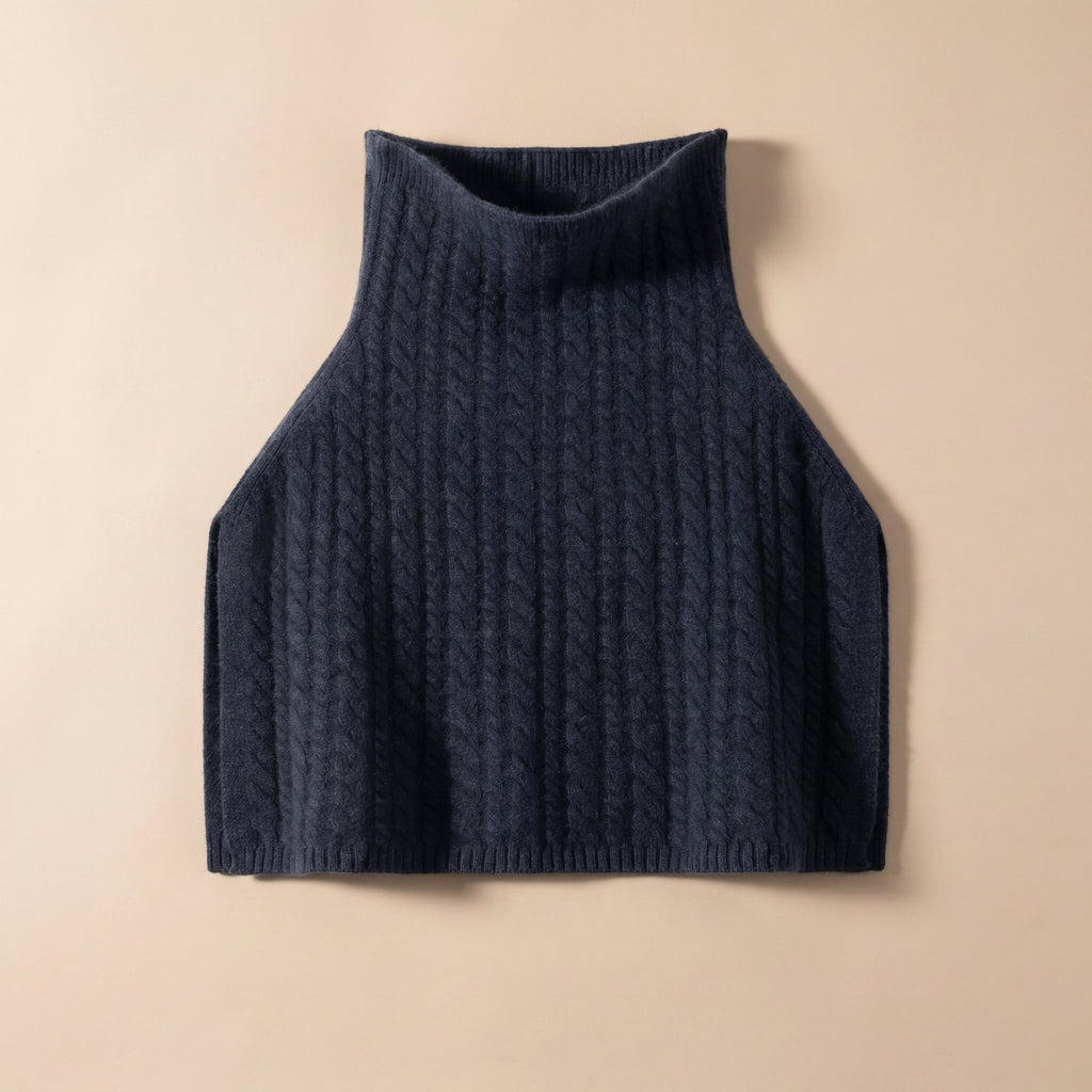 Poncho pull femme maille torsadée bleu marine, posé à plat avec un col roulé.