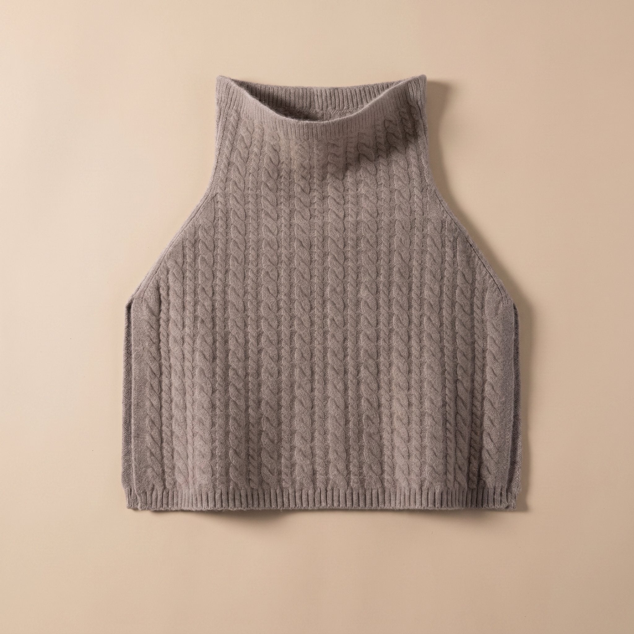 Poncho pull femme maille torsadée taupe, présenté à plat sur un fond beige clair.