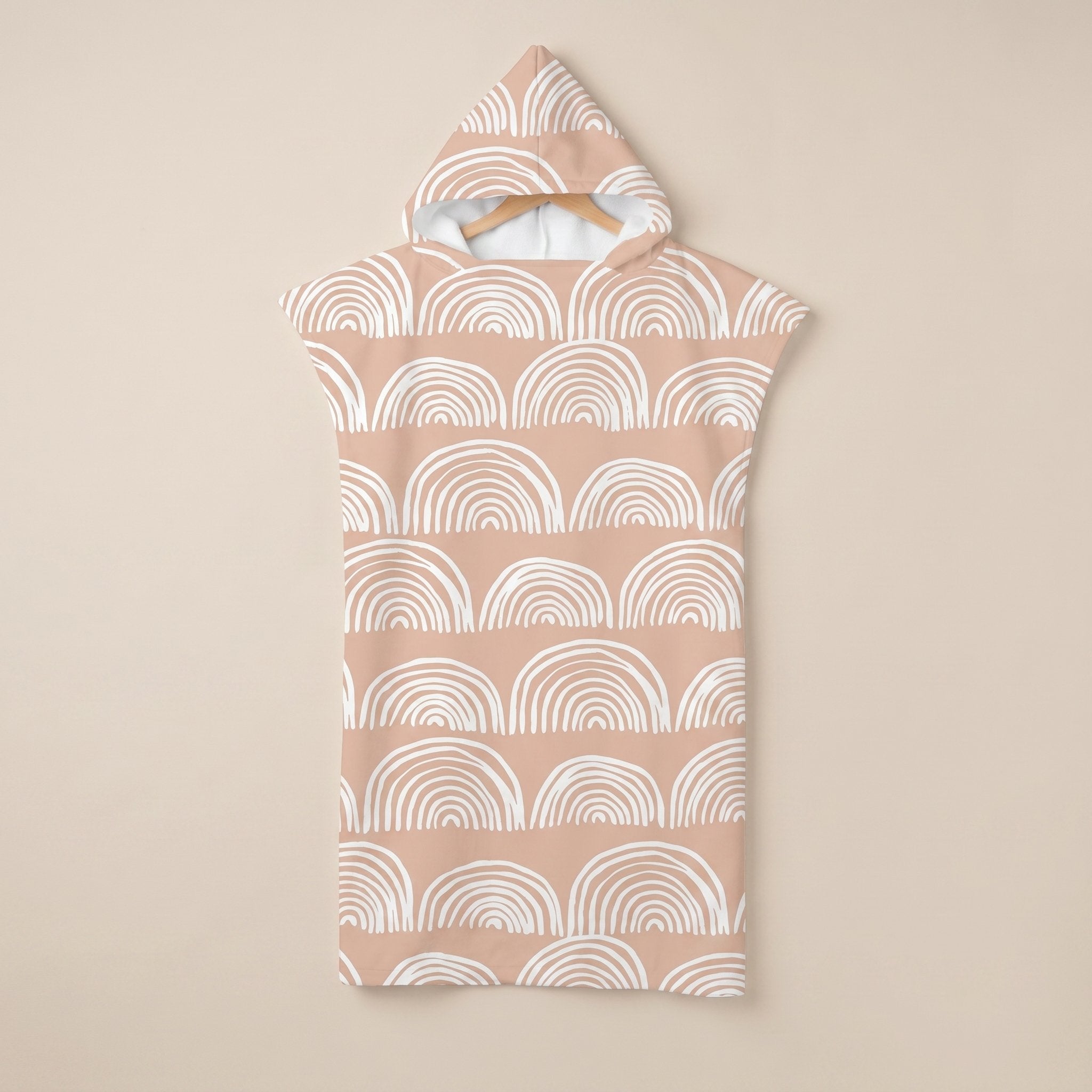 Poncho serviette a capuche motif Arches pêche, suspendu sur un cintre, vue de face.