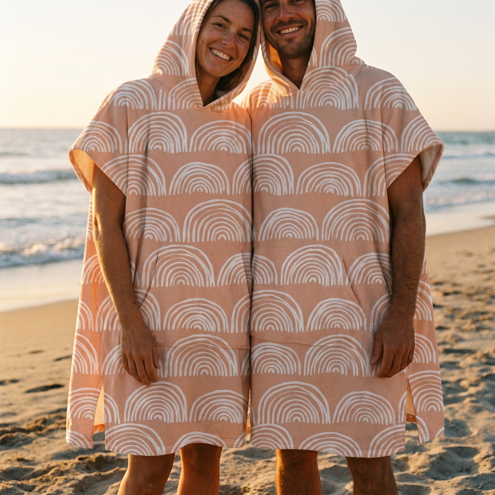Poncho serviette a capuche motif Arches pêche, porté par un homme et une femme côte à côte, souriant sur la plage.