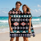Poncho serviette a capuche motif aztèque rose et turquoise, porté par un homme et une femme, debout face à la mer.