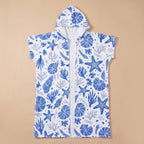 Poncho serviette à capuche motif coquillages bleus, posé à plat, vue de face sur fond uni.