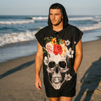 Poncho serviette à capuche motif crâne couronne de fleurs, porté par un homme marchant de profil sur le sable.