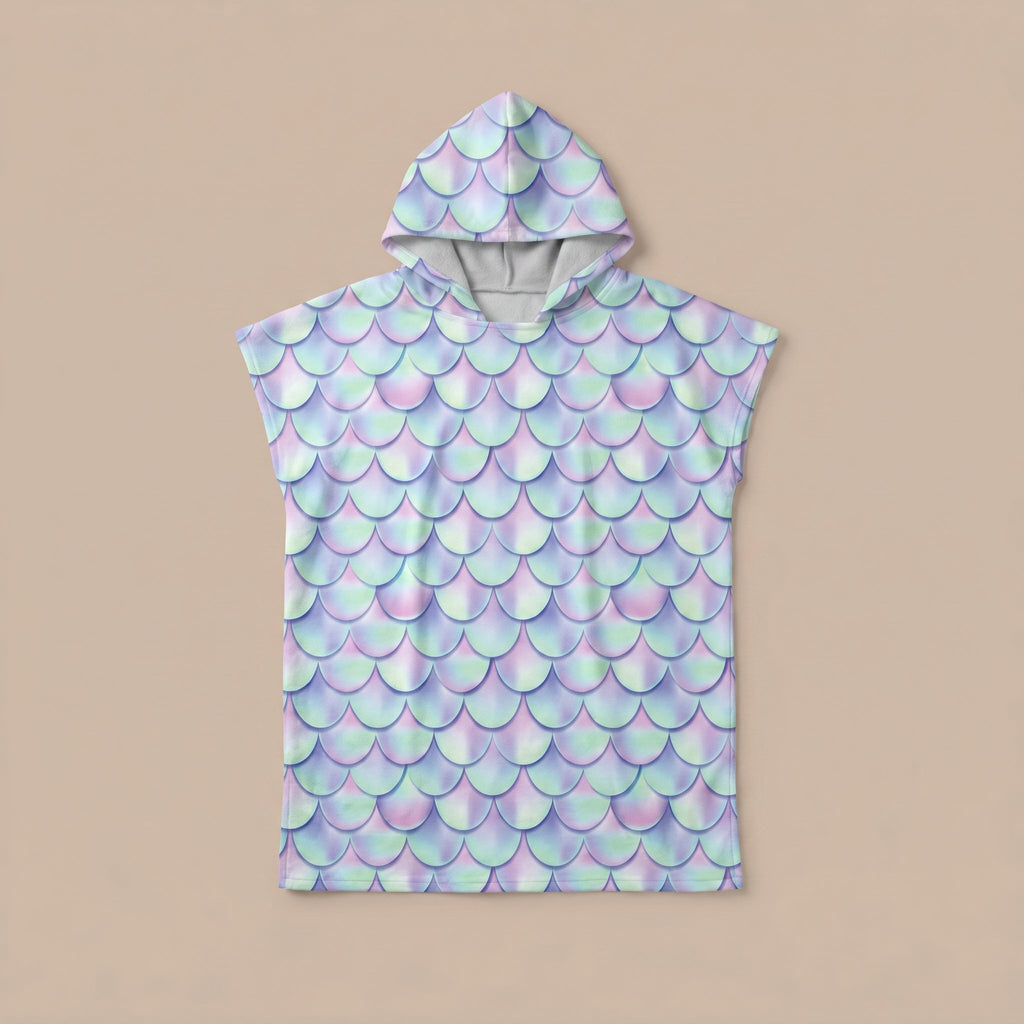 Poncho serviette a capuche motif écailles lilas, posé à plat sur un fond uni beige clair.