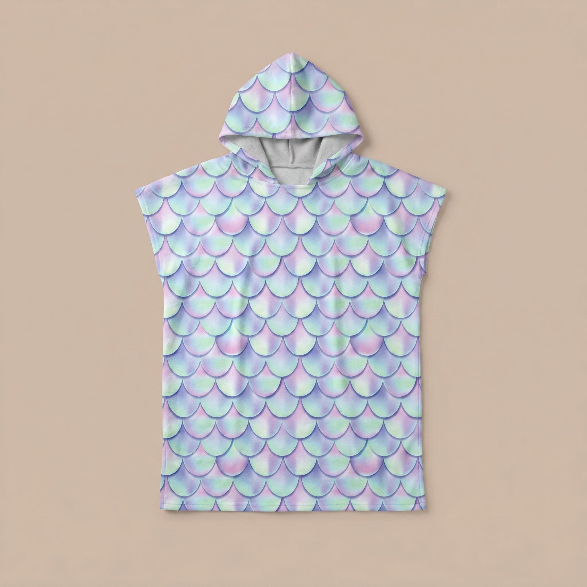 Poncho serviette a capuche motif écailles lilas, posé à plat sur un fond uni beige clair.