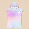 Poncho serviette a capuche motif écailles arc-en-ciel pastel, présenté à plat sur un fond beige uni.
