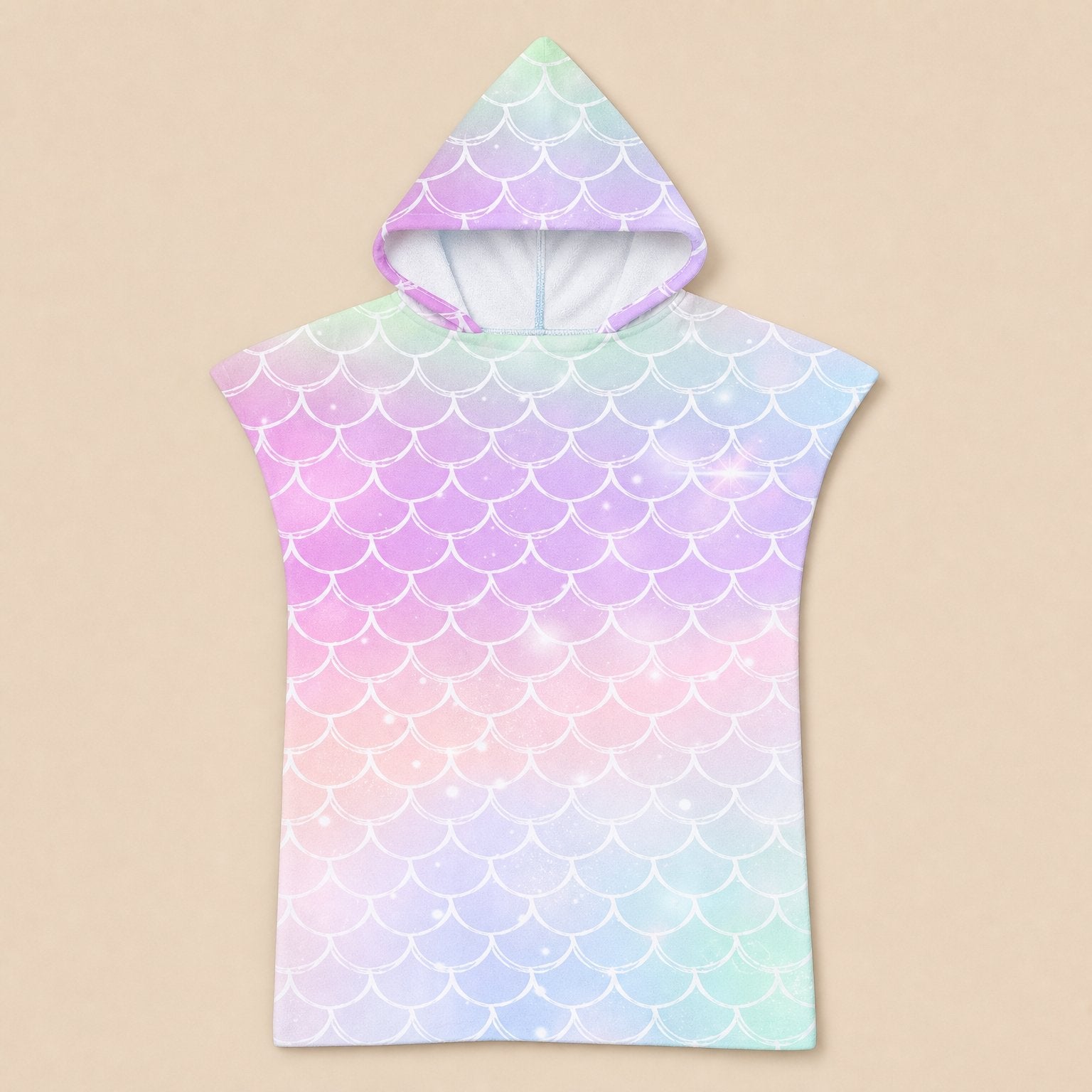 Poncho serviette a capuche motif écailles arc-en-ciel pastel, présenté à plat sur un fond beige uni.